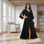 A woman modeling a floor-length black gown with a V-neckline, draped cap sleeves, a gathered waist, and a high front slit, photographed against a plain white background.