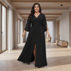 A woman modeling a long black maxi dress with a V-neckline, elbow-length sleeves, side slit details,